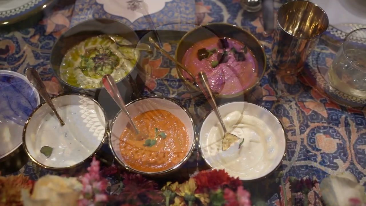 Bowls of dips on a patterned cloth, seen from above.